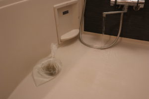 透明のビニール袋に水を入れてお風呂場の排水溝に置いて蛇口からお湯を流している写真