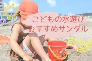 娘が海の砂浜に座ってお砂場道具で遊んでいるところ
